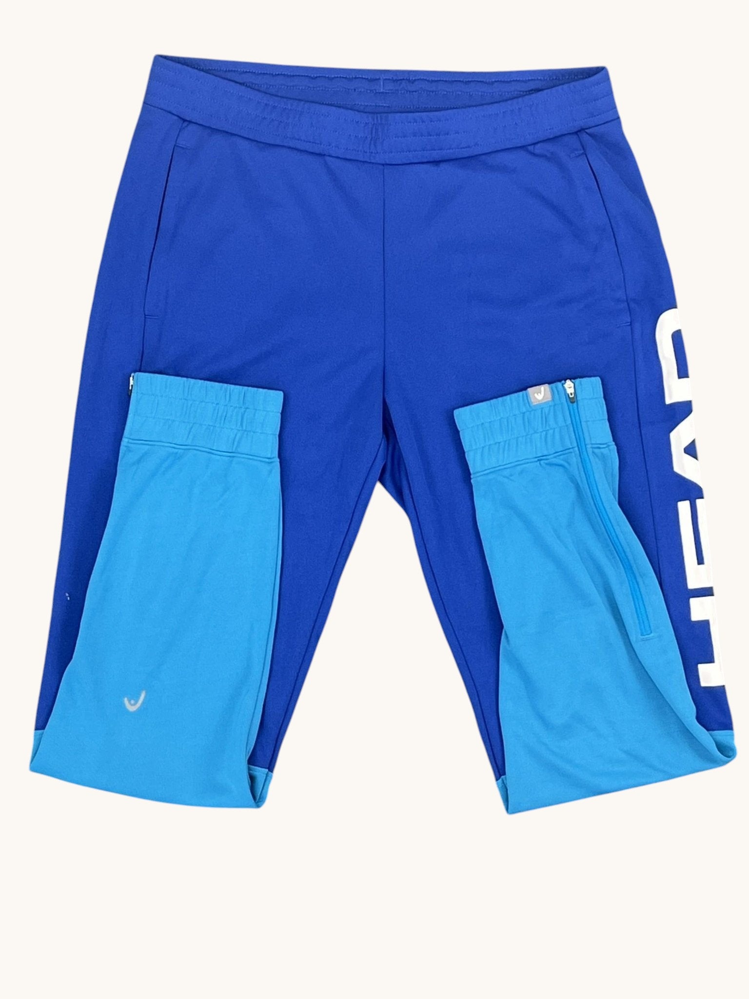 Head blue tennis tracksuit bottoms with elastic waistband and side pockets. Two-tone blue design.