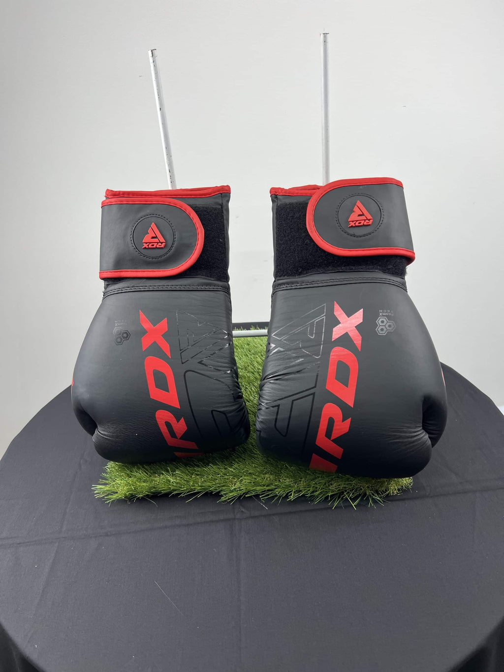 Front view of black and red RDX boxing gloves standing upright