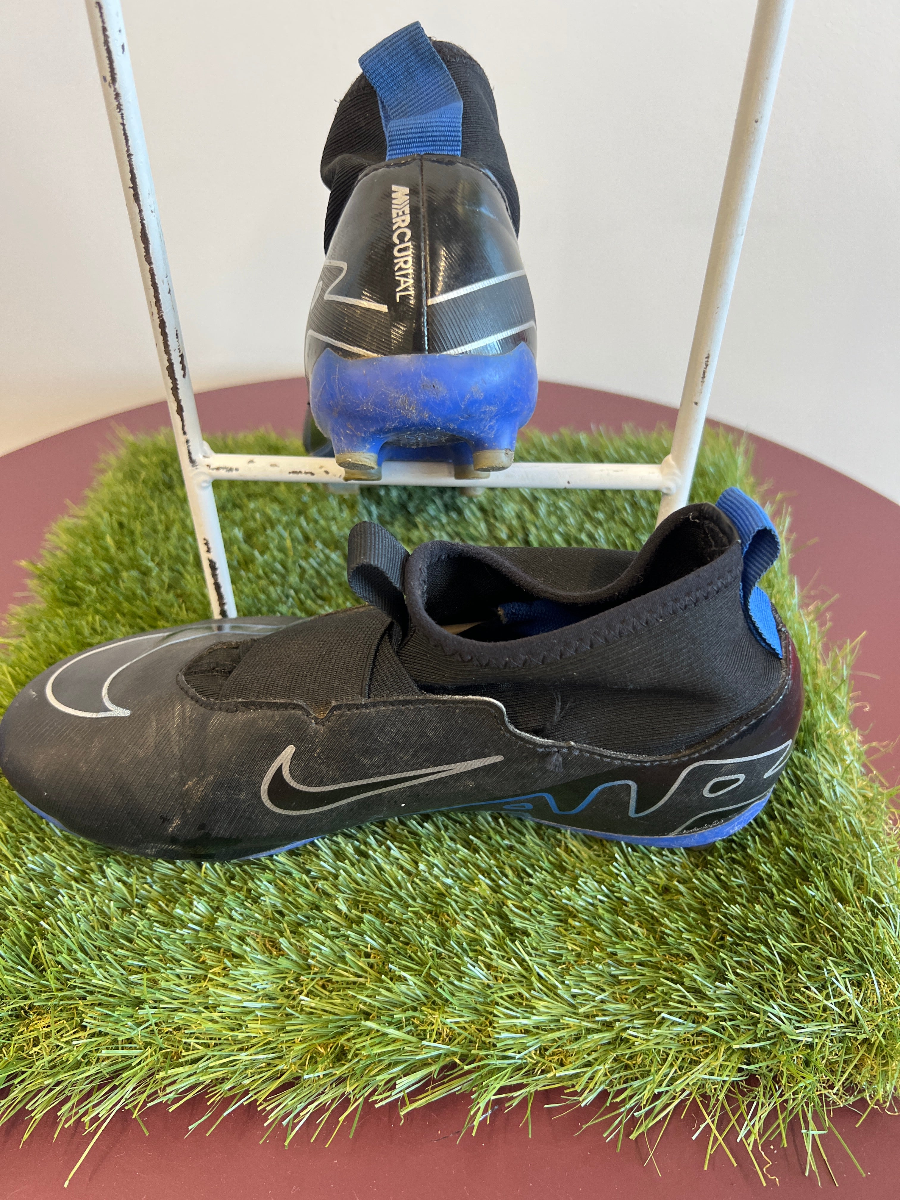 Side and back view of black and blue Nike Mercurial football boots showing high collar and pull tab