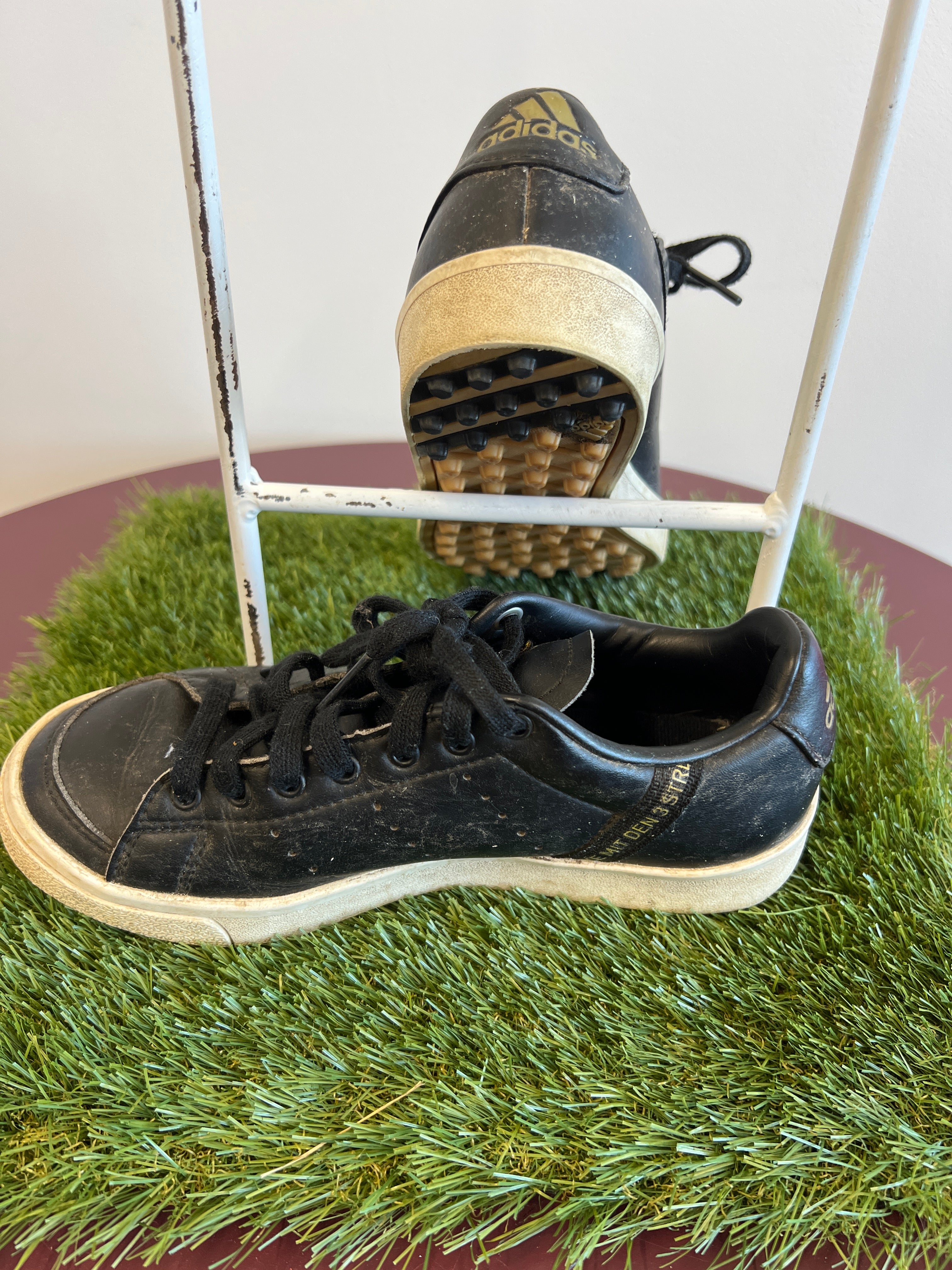 Side view of worn black leather kids adidas Astro Boots showing gold branding and textured sole