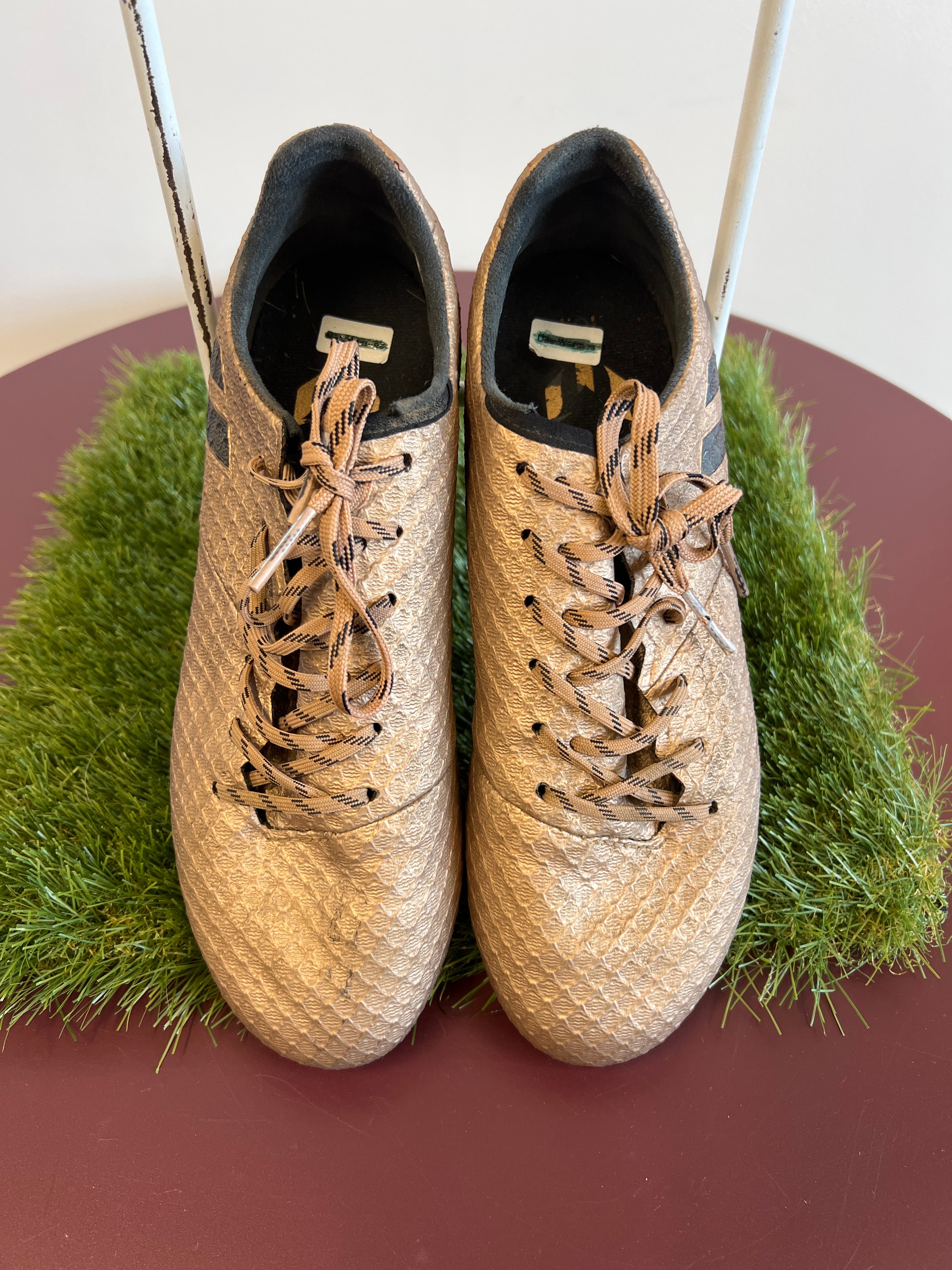Front view of kids adidas football boots showing gold textured upper and patterned laces