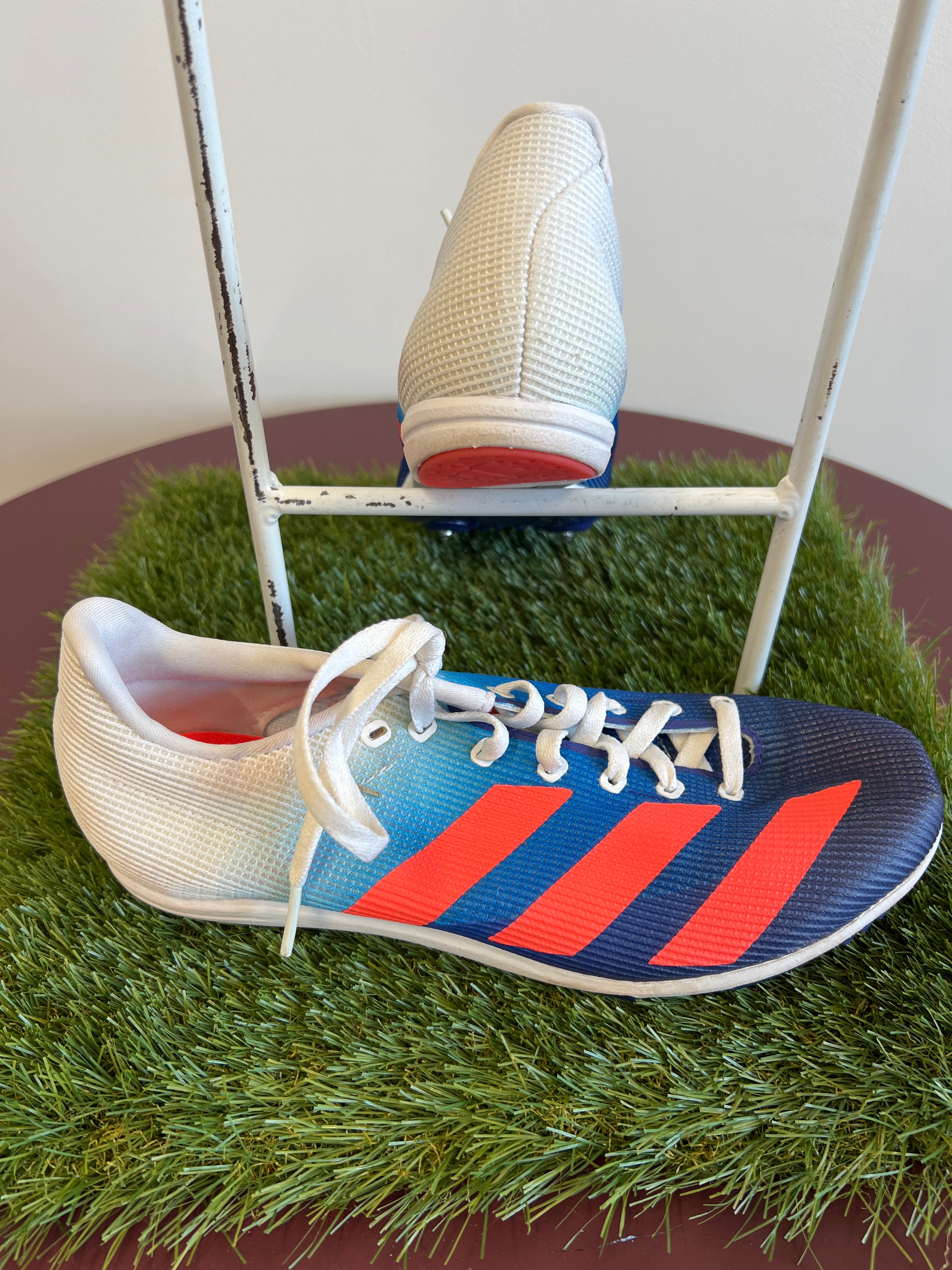 Side view of a single kids adidas running spike shoe showing gradient colour and design details