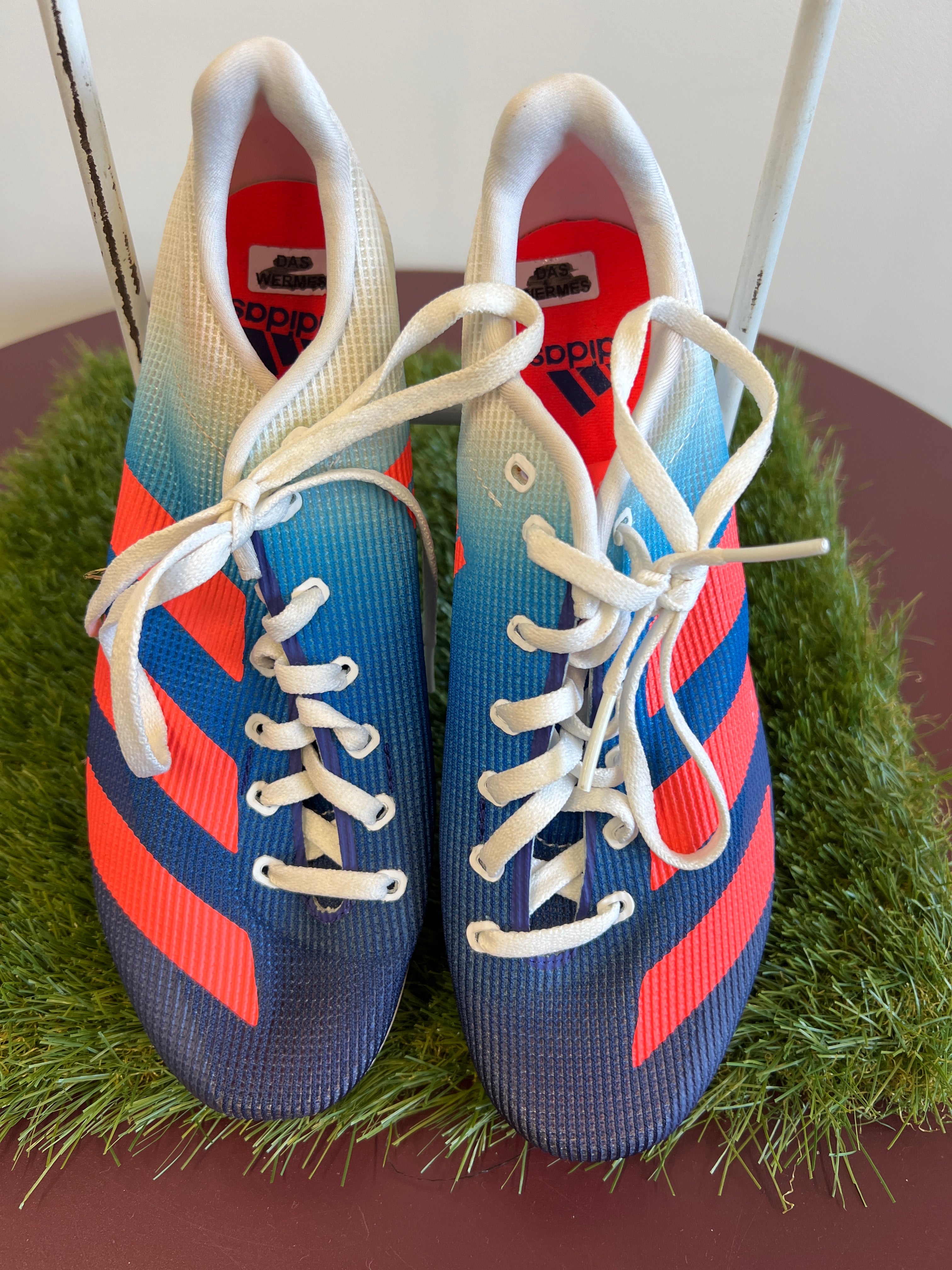 Top view of kids adidas running spikes in blue gradient with red stripes and white laces