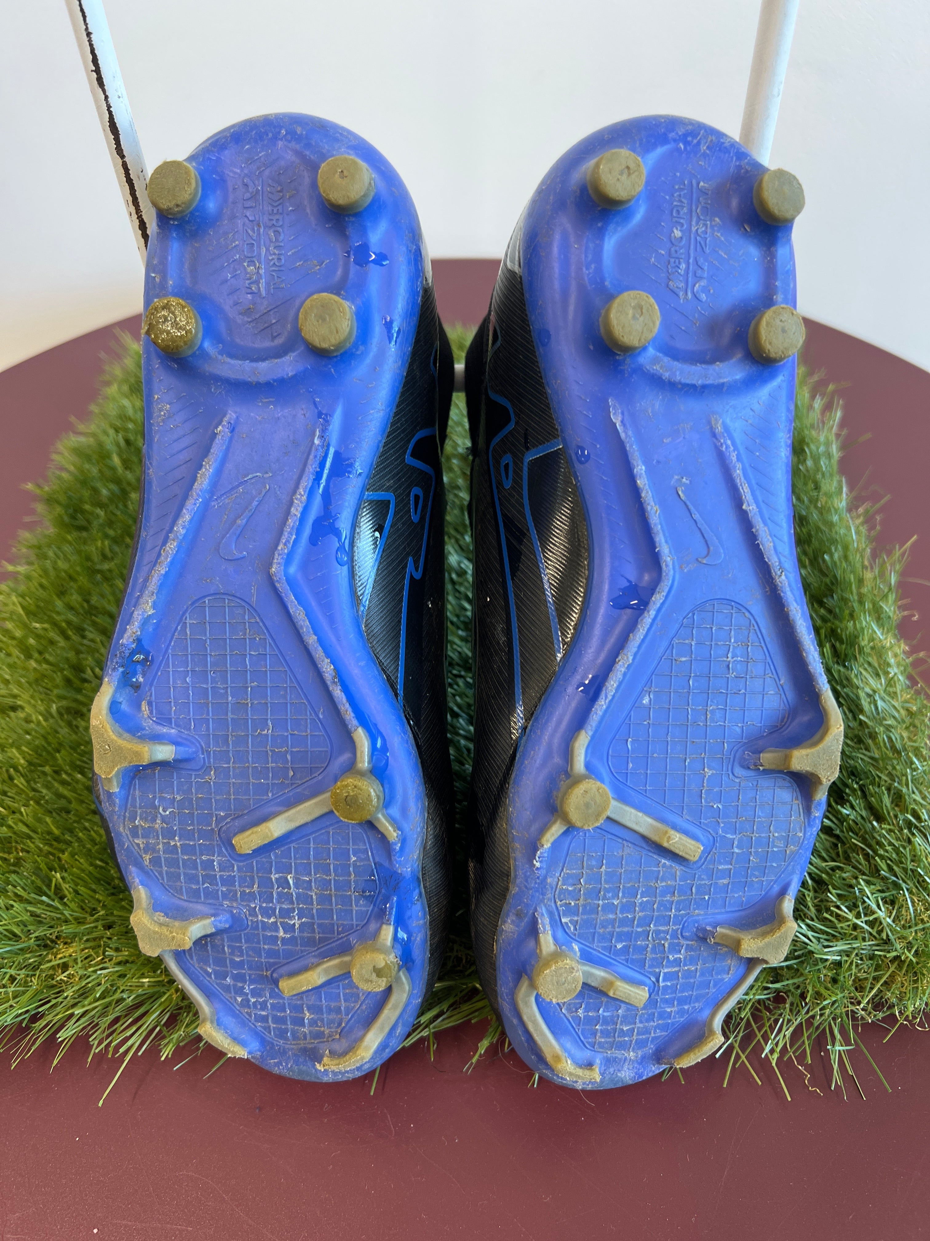Underside view of blue soleplate with moulded studs on kids Nike Mercurial football boots