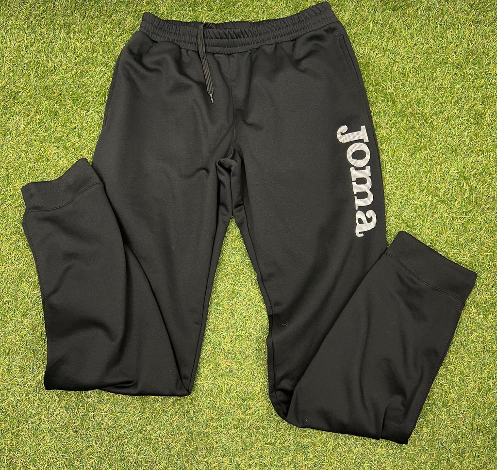 Pair of black Joma tracksuit bottoms with logo on grass background