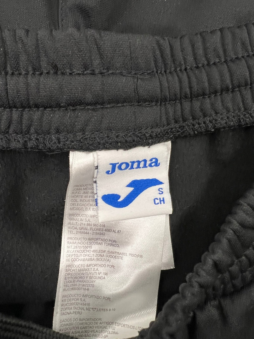 Joma brand label showing size small inside waistband of black trousers