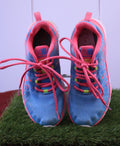 Front view of blue and pink Karrimor kids trainers with tied laces on artificial grass