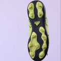 Side and sole view of neon yellow kids Adidas football boot with black studs