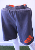 Front view of grey adidas sports shorts with orange logo and elastic waistband
