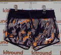 Nike kids running shorts in navy and orange pattern with white swoosh logo displayed on hanger