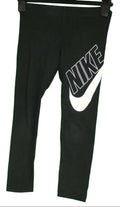 Front view of black Nike kids tracksuit bottoms with large white NIKE logo and swoosh
