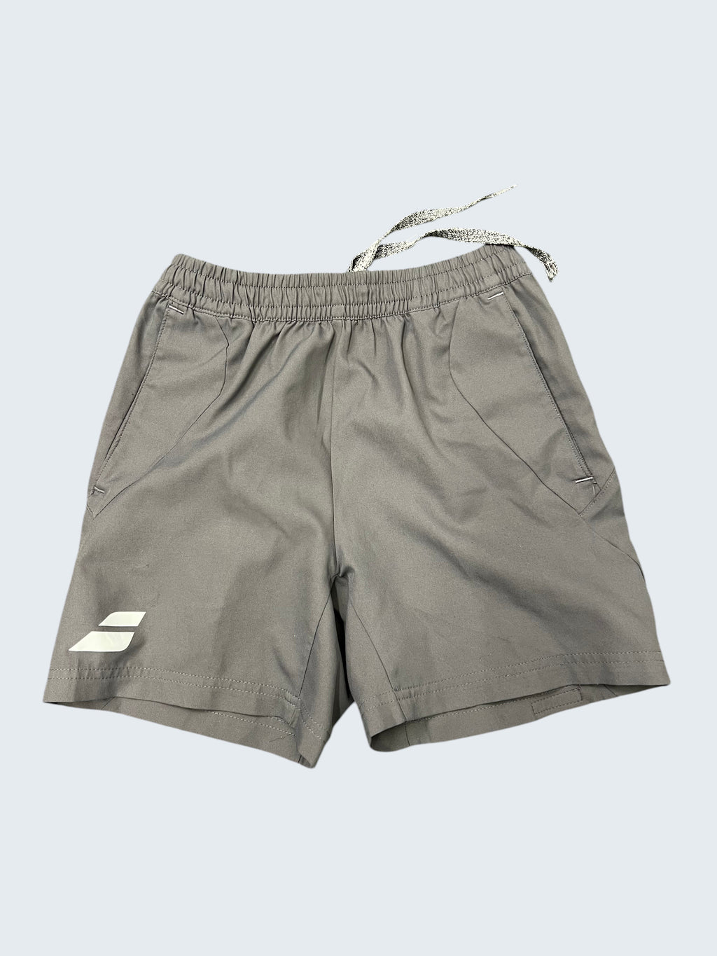 Kitround Babolat Kids Grey Training Shorts with elastic waistband and drawstring, featuring side pockets and logo detail.