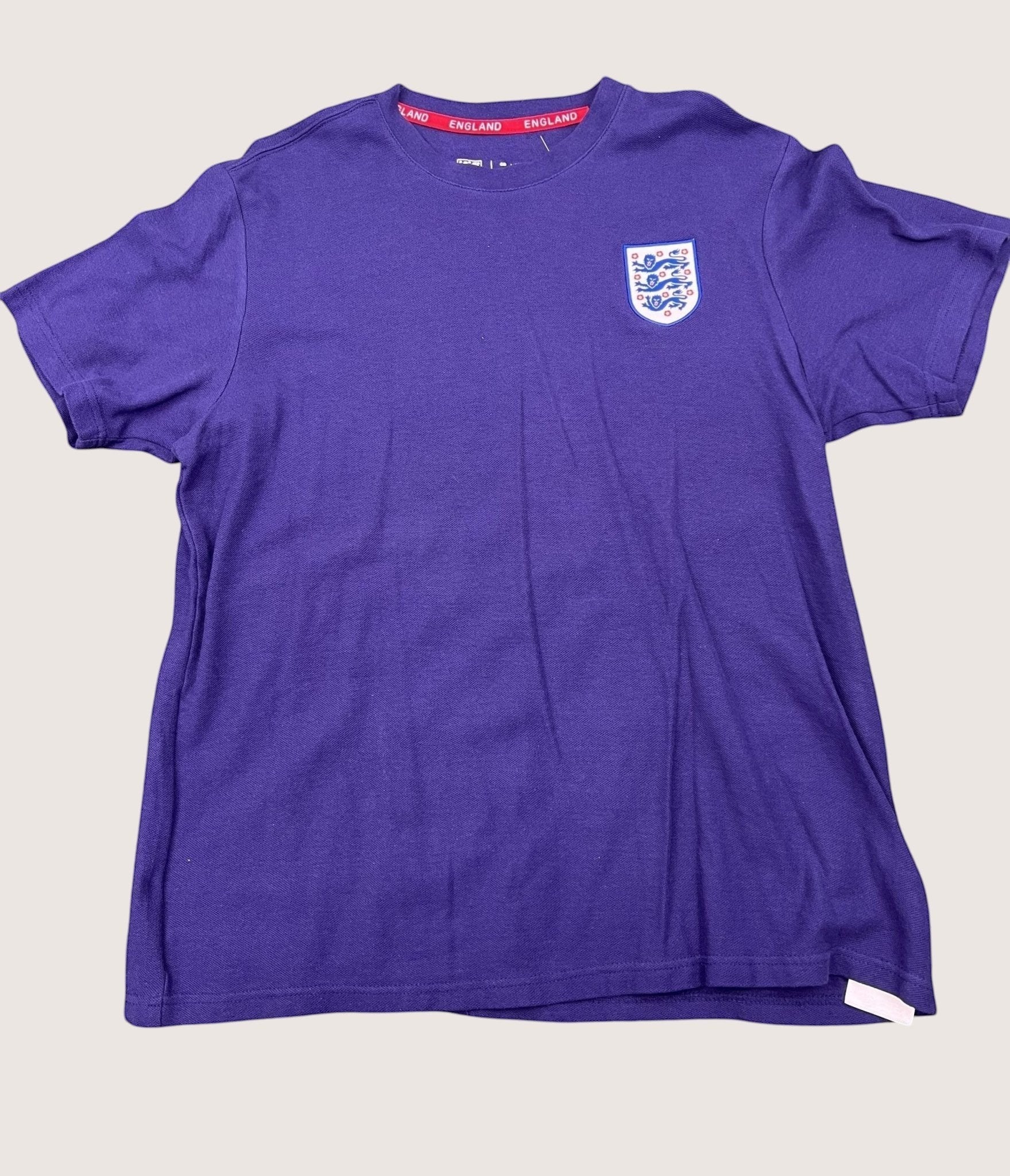 kitround dark blue England football t-shirt with official FA crest and red inner neck detailing on grass background