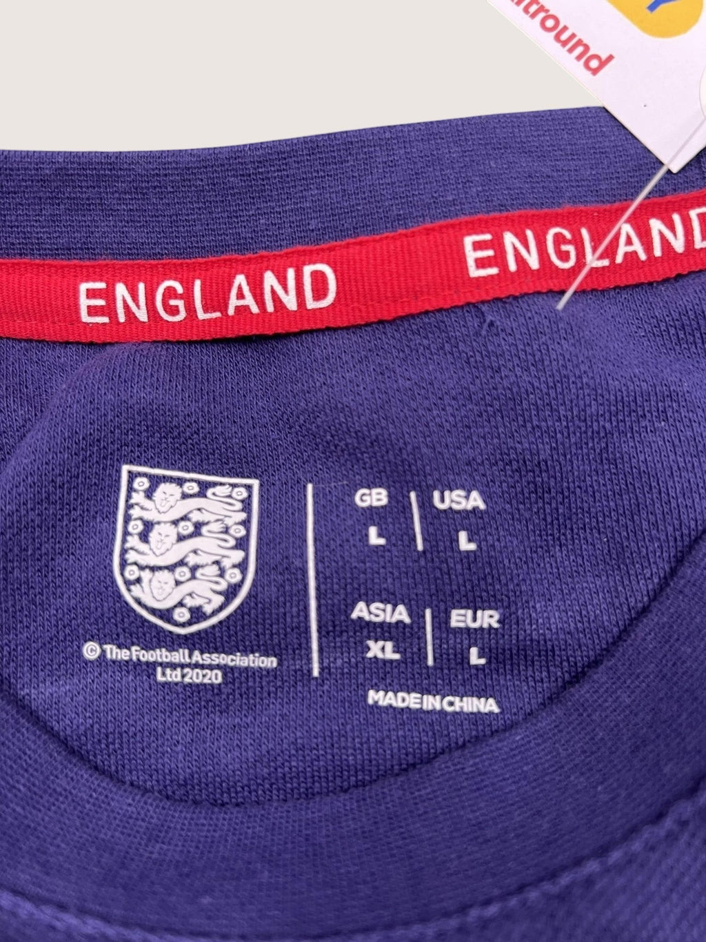 kitround dark blue England football shirt with red neck tape, FA crest, and size label details.