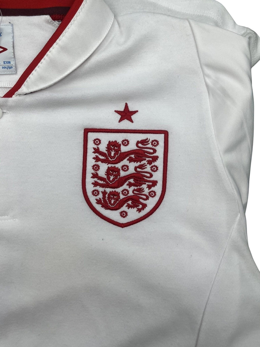 kitround white Umbro England football shirt with red collar trim and embroidered Three Lions crest on the chest.