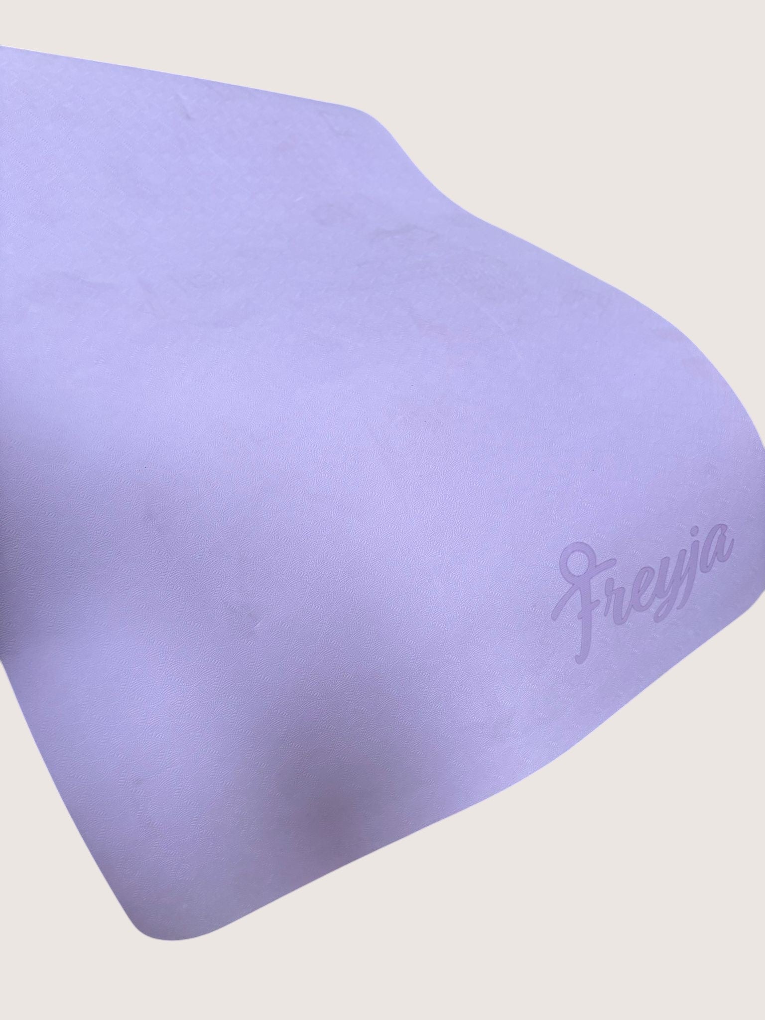 Freya purple yoga mat with a textured surface and embossed logo, offering cushioning and grip for exercise.