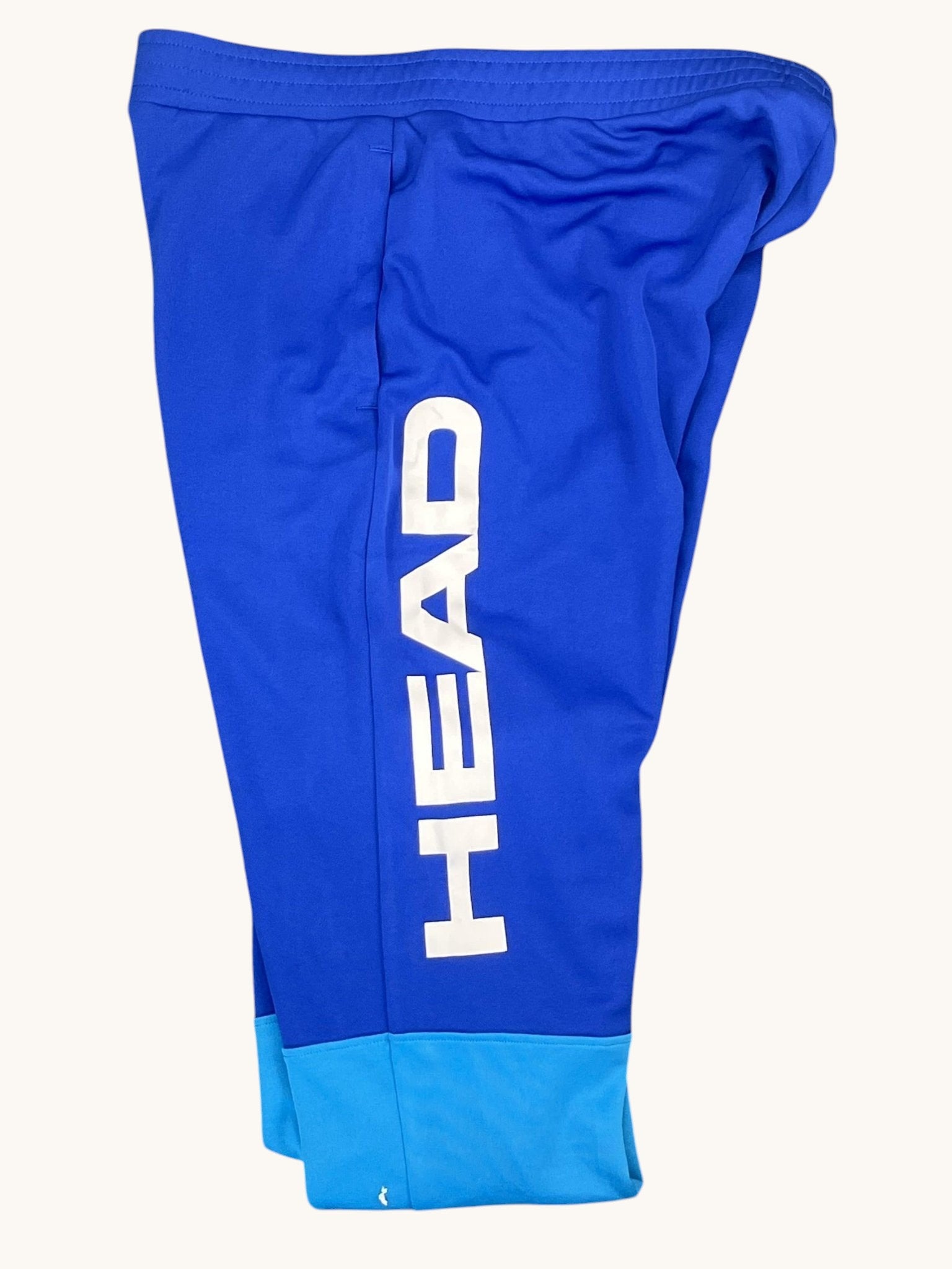 Head blue tennis tracksuit bottoms with elastic waistband and side pockets. Two-tone blue.