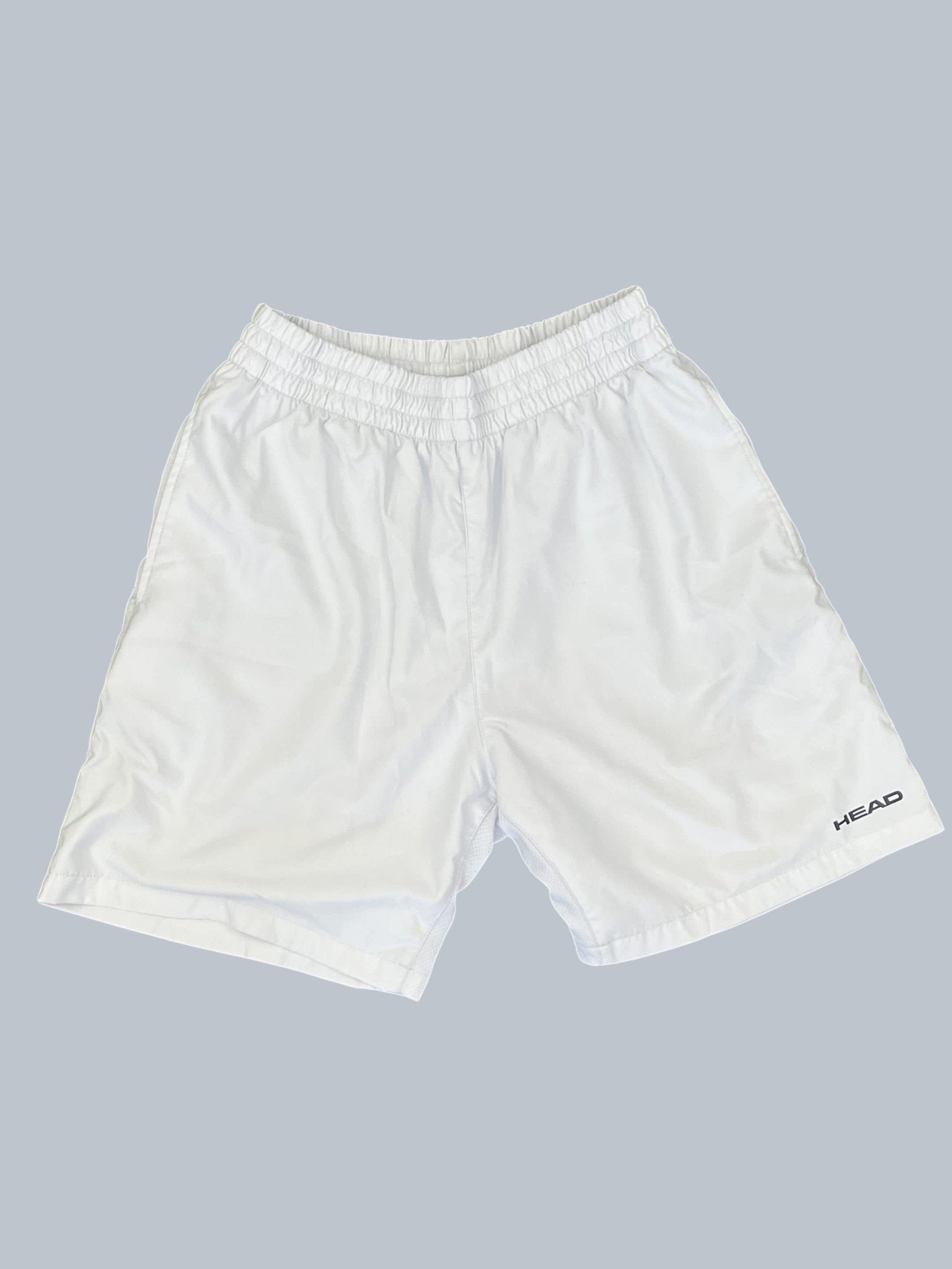 White Head tennis shorts with elastic waistband and breathable fabric. Features Head logo on the right leg.