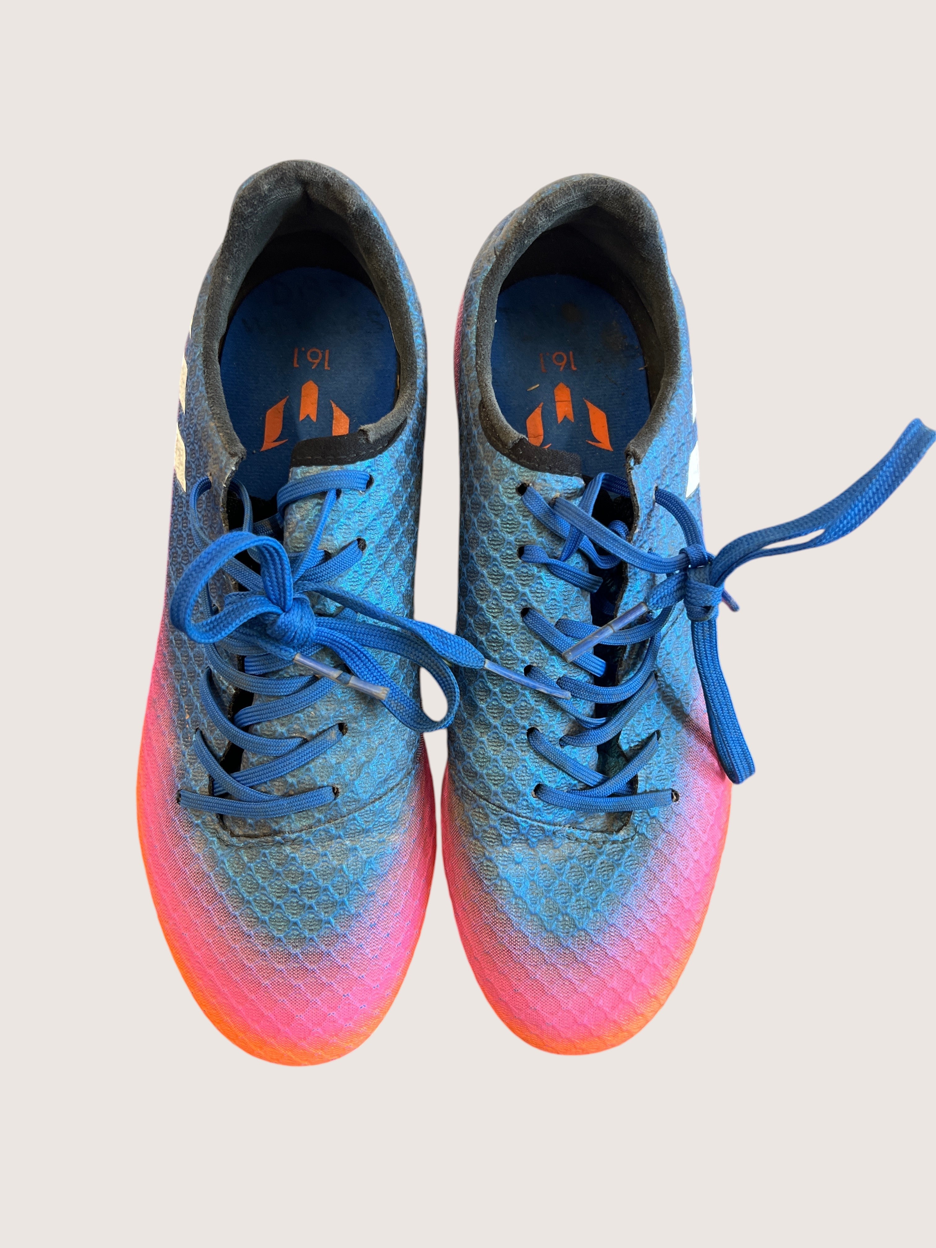 kitround kids adidas football boots with textured blue, pink, and orange synthetic upper and blue laces on grass.