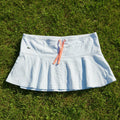 Lacoste light blue tennis skirt with coral drawstring and flared hem. Features breathable fabric and crocodile logo.