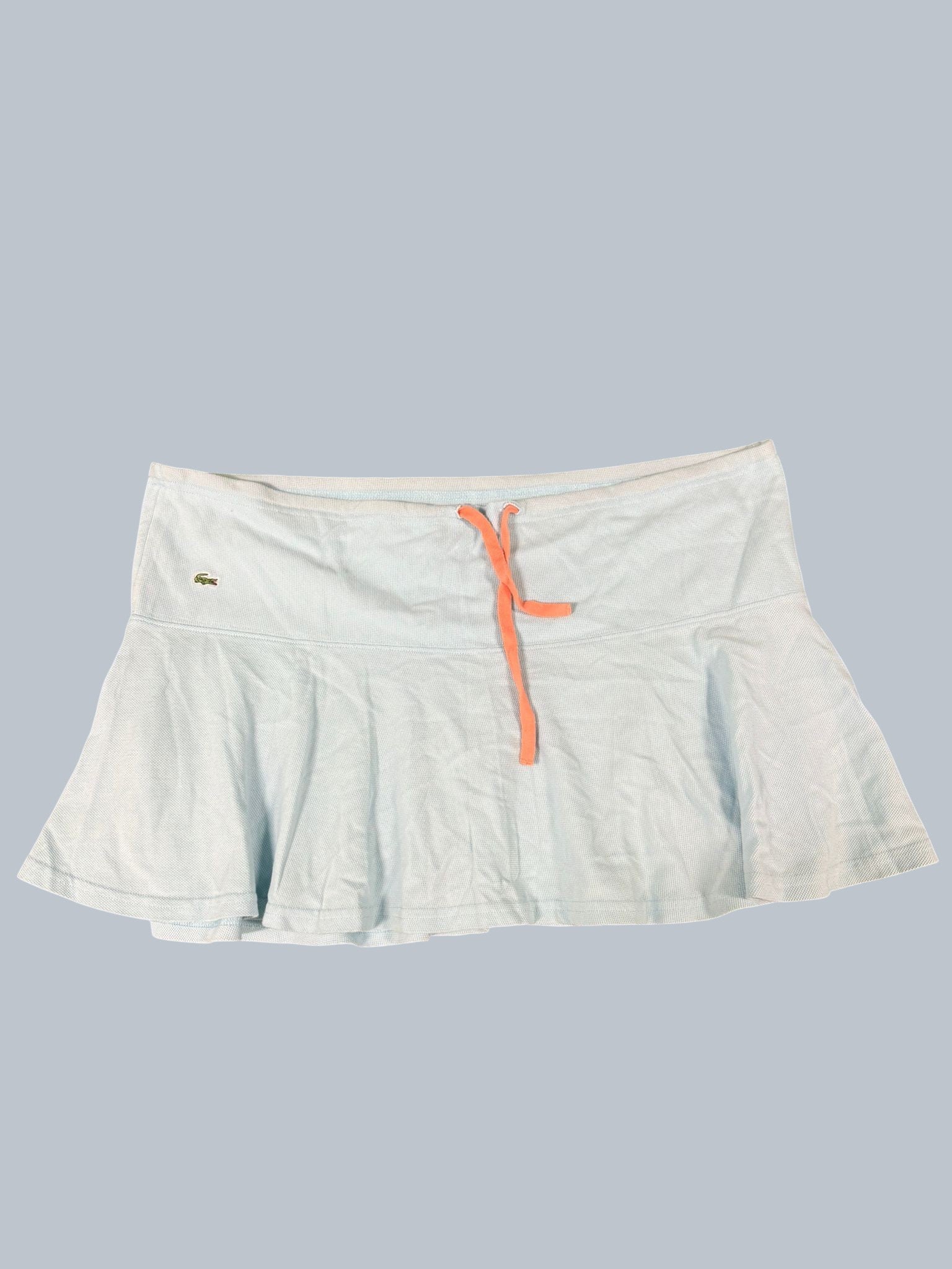 Lacoste light blue tennis skirt with coral drawstring and flared hem. Features breathable fabric and crocodile logo.