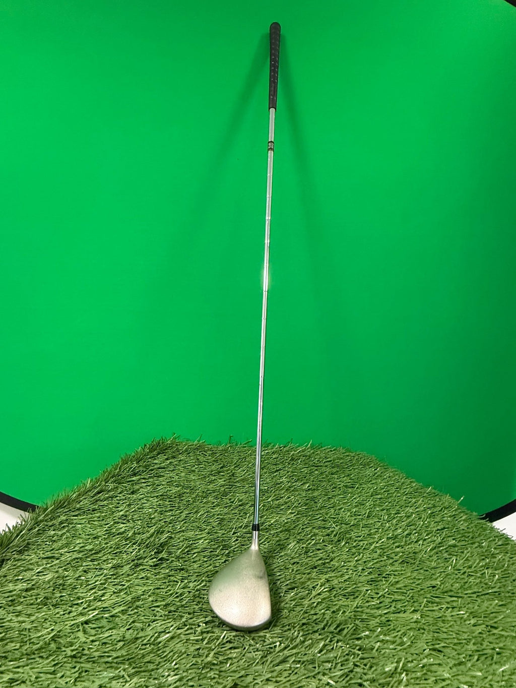 Used Longridge driver golf club standing upright on artificial grass with green background