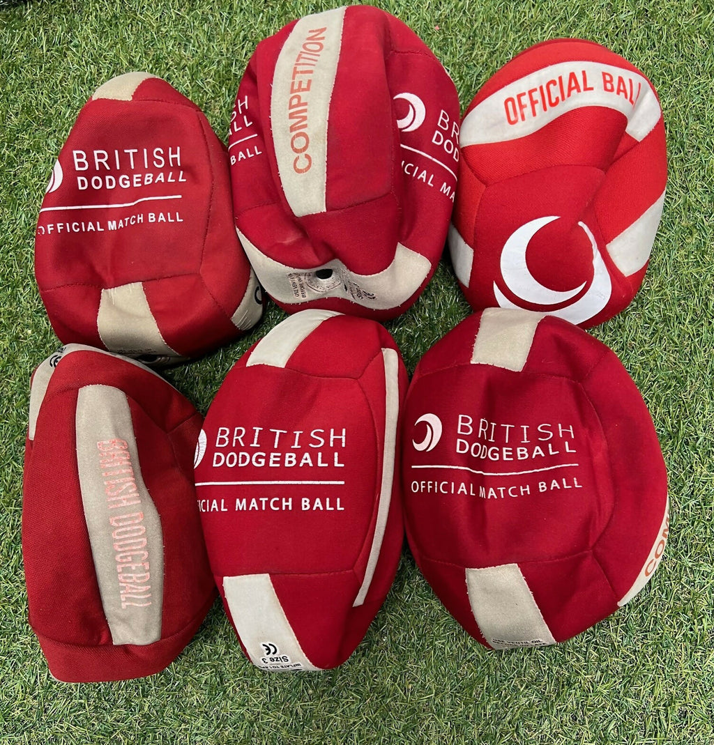 Set of six red and cream British dodgeballs laid out on grass, labelled official match balls, size 3