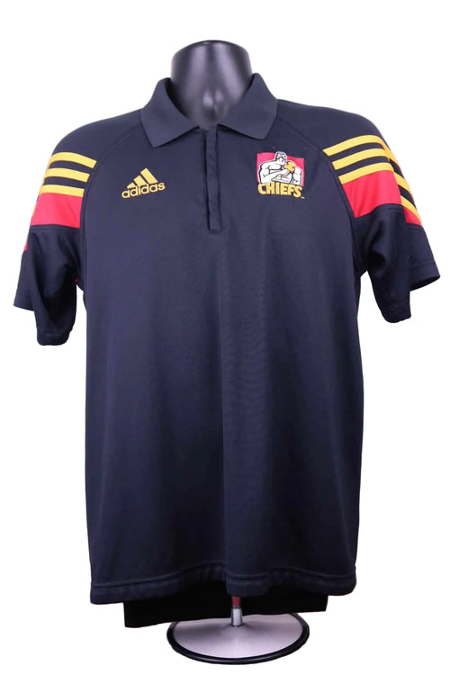 Front of adidas Chiefs black polo shirt with yellow and red shoulder details and logos