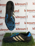 Pair of black adidas football boots with blue soles and white stripes, side and sole view on artificial grass with kitround branding.