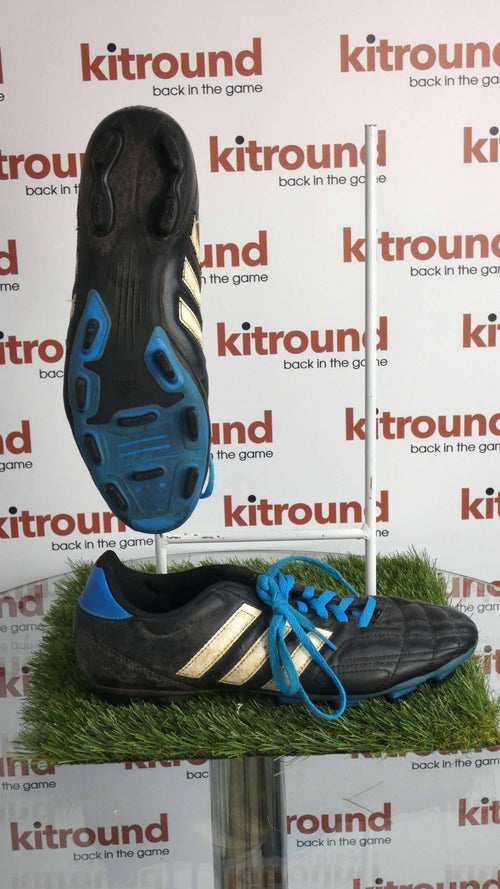 Side and sole view of black adidas football boots with blue highlights and white stripes, displayed on artificial grass with kitround branding.