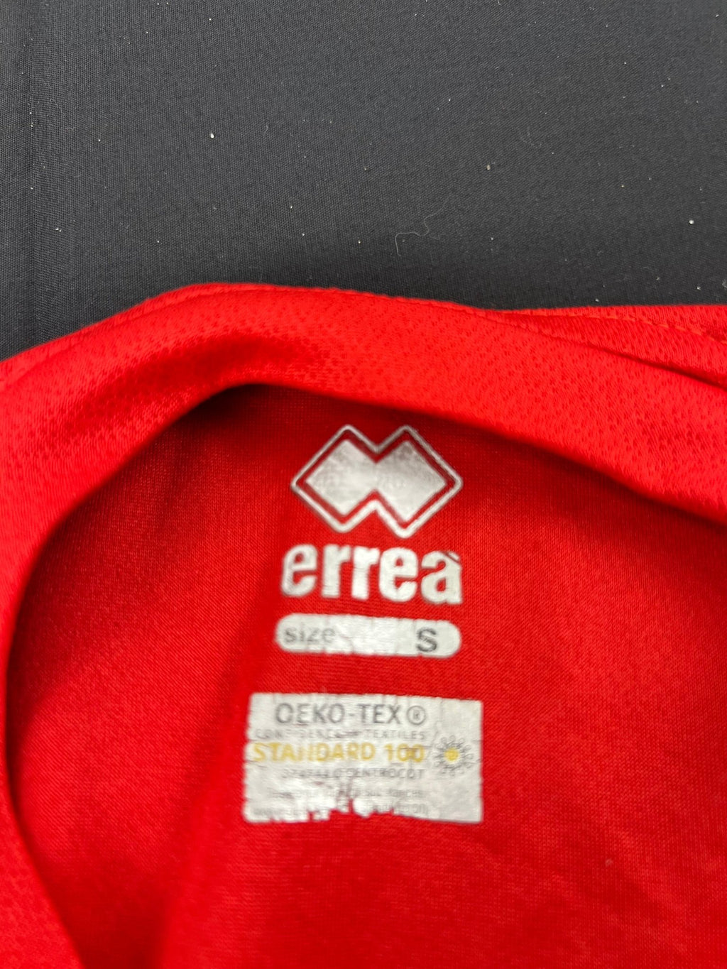 Close-up of Errea brand and size S label inside red Volleyball England t-shirt