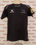 Front view of black Newcastle Falcons rugby t-shirt by Gilbert with white sponsor logos and AVIVA Premiership patch on sleeve on mannequin.