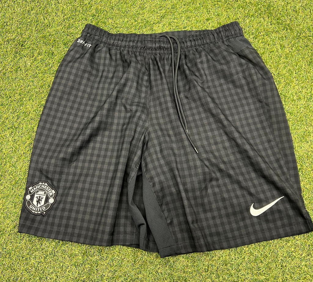 Front view of black Nike dri fit Manchester United shorts with check pattern and embroidered logos, size XL