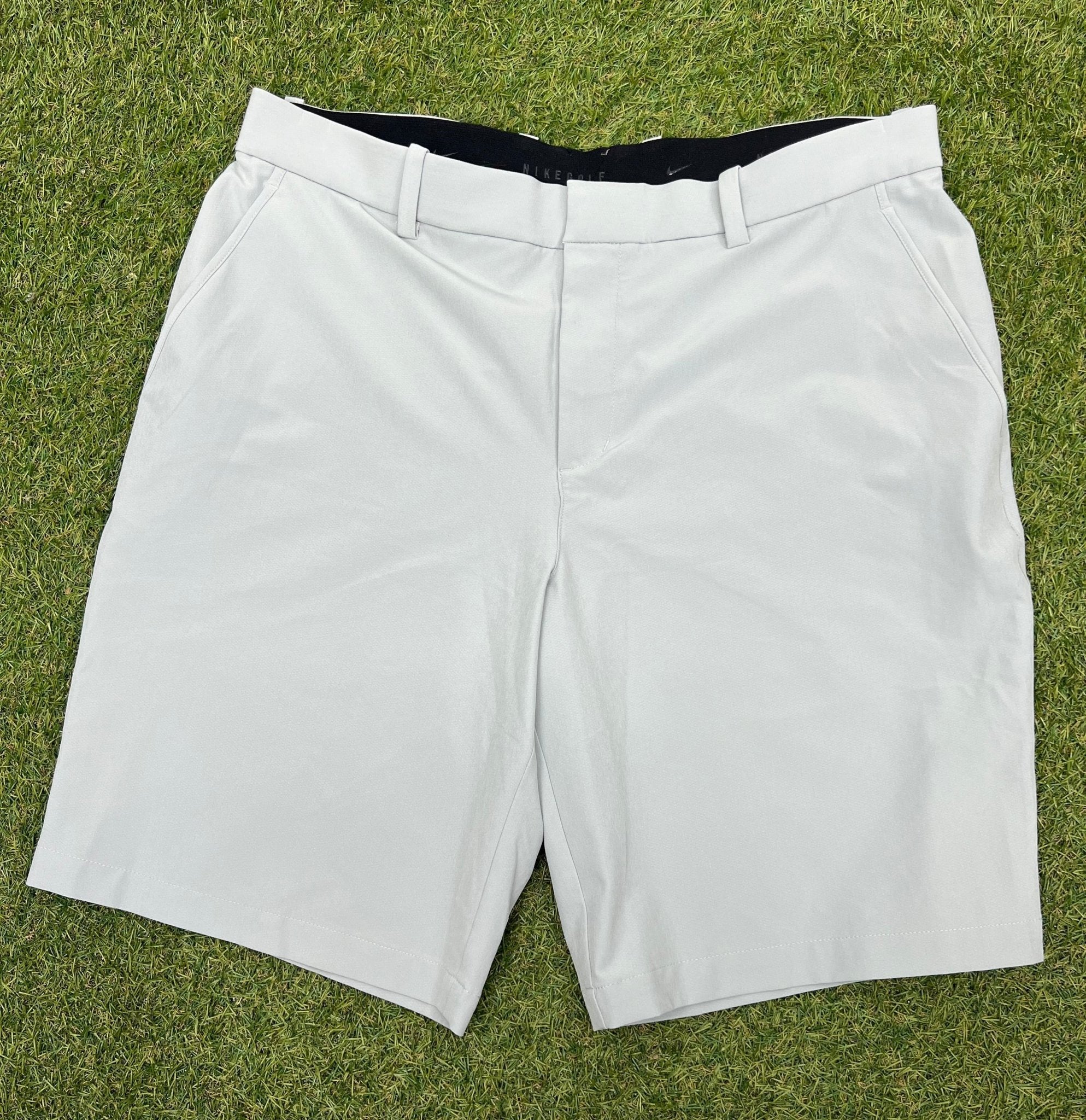 Front view of grey Nike golf shorts on grass
