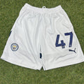 White Puma Manchester City football shorts with number 47 and club crest on grass