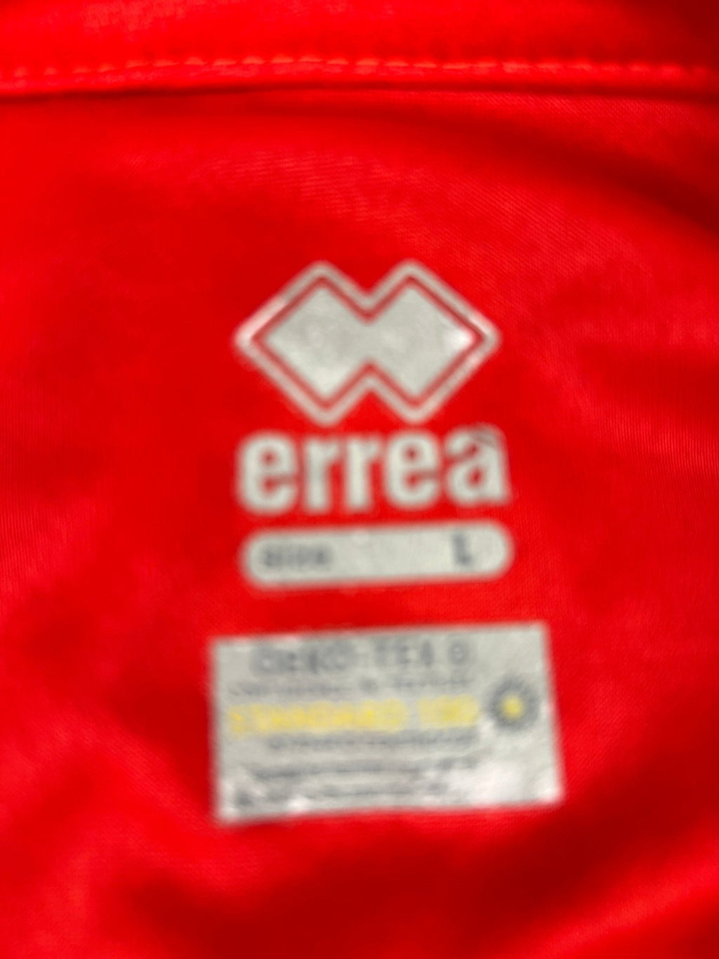 Close-up of internal Erreà brand and size L label on red volleyball polo shirt