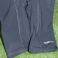 Black Speedo Vanquisher jammer swim trunks with visible stitching detail, laid flat on green artificial grass.