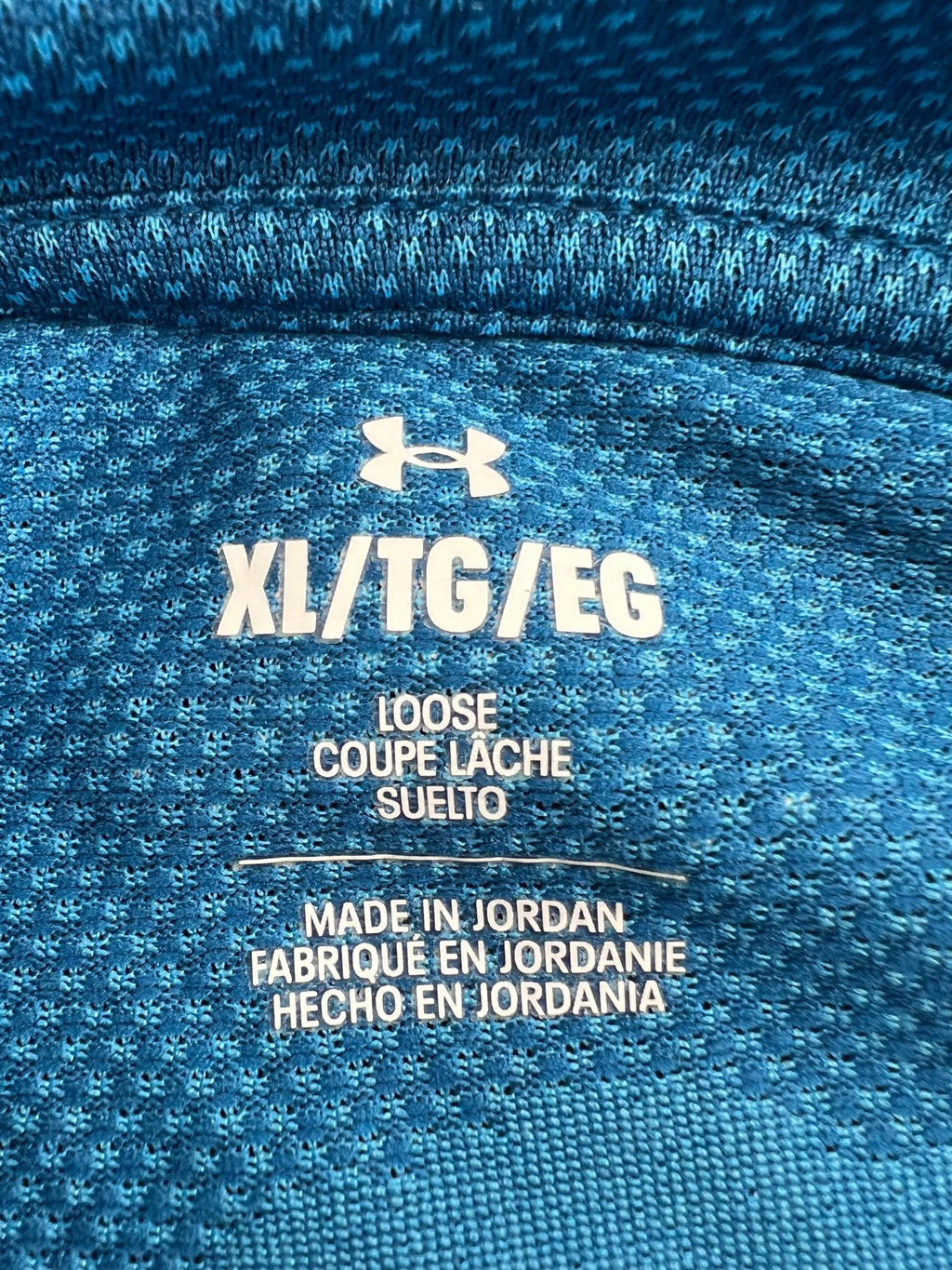 Close-up image of size and care label on blue Under Armour 1/4 zip top