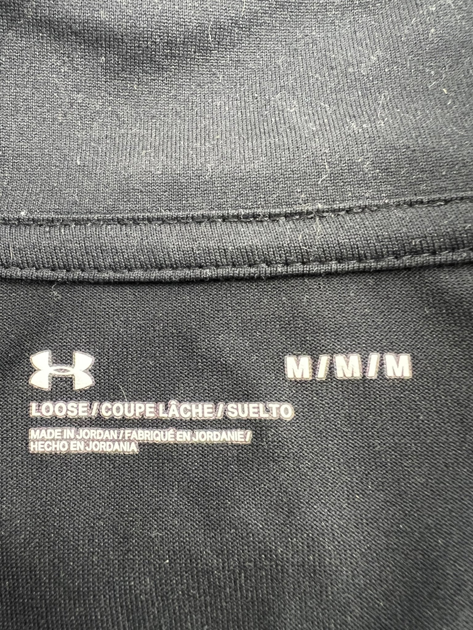 Clothing label indicating medium size, loose fit, and Under Armour branding