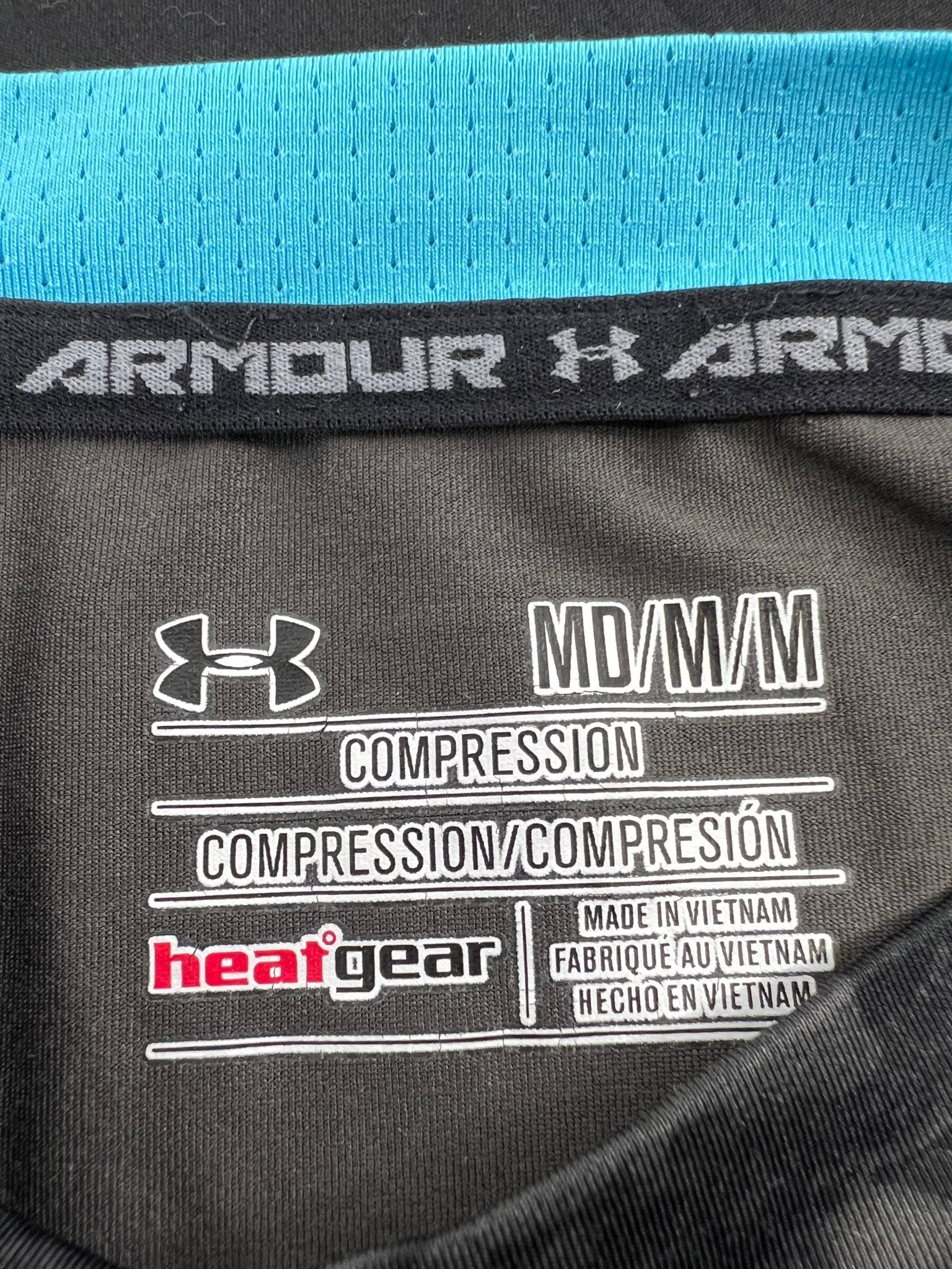 Close-up of Under Armour HeatGear compression top interior label showing size medium