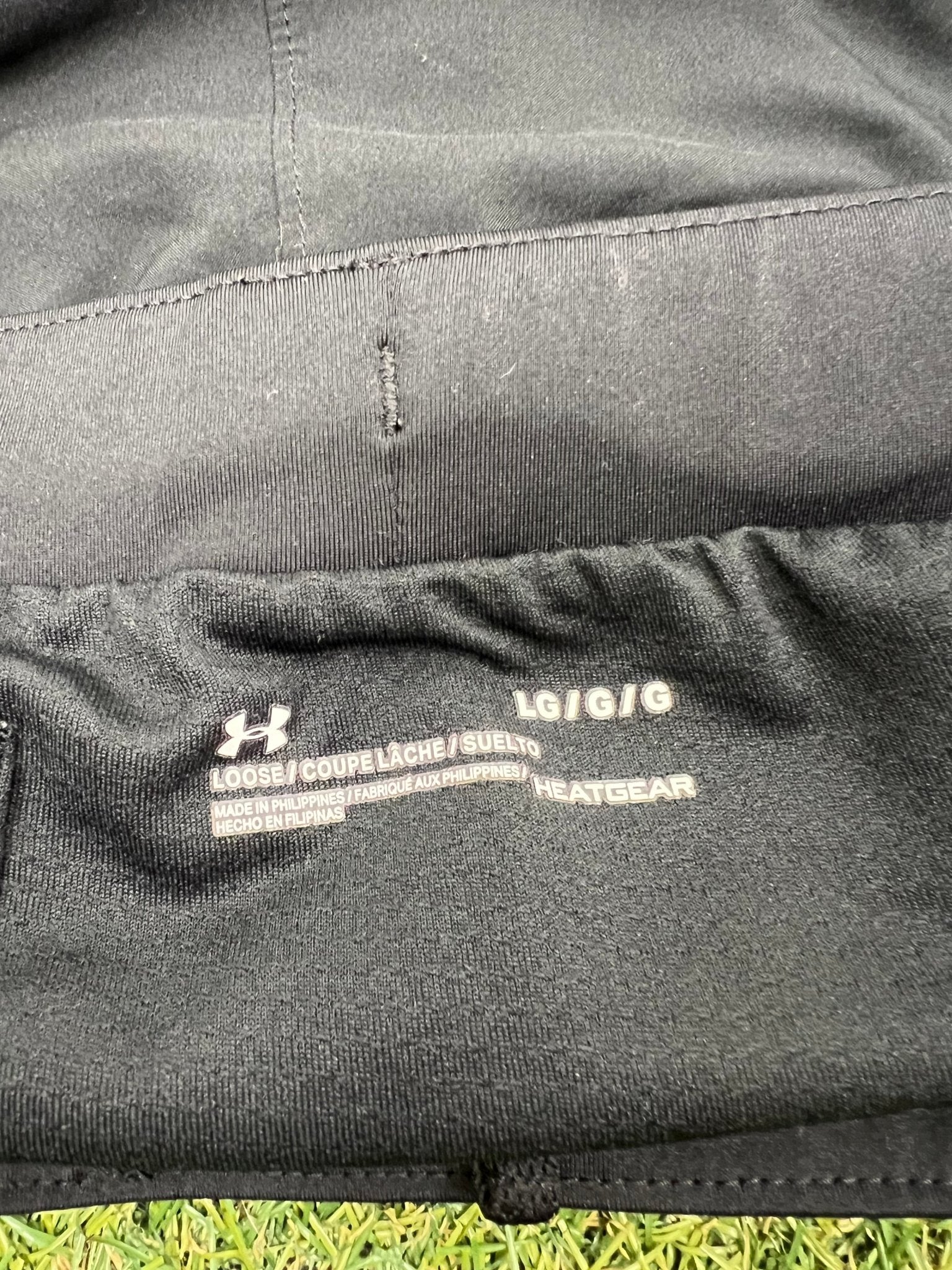 Closeup of Under Armour brand label and size tag on black shorts
