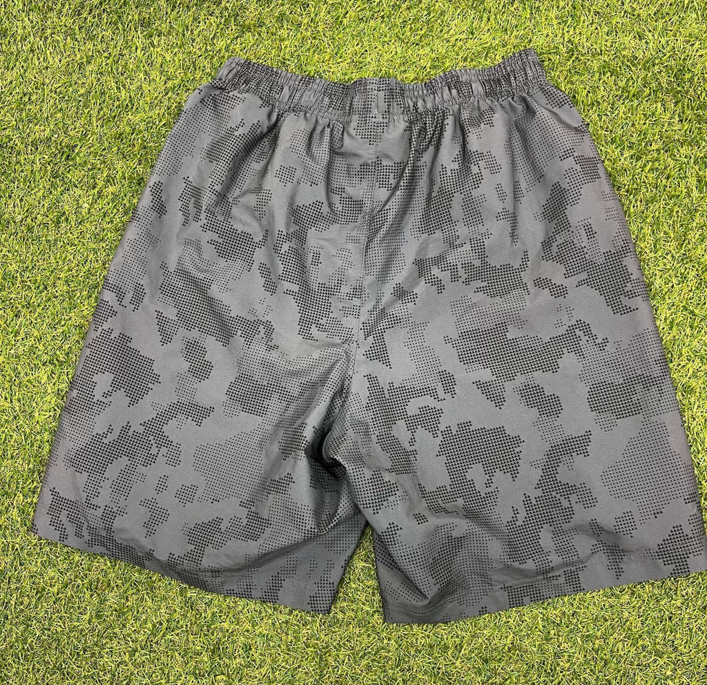 Back view of men's Under Armour grey camo loose fit shorts on grass background