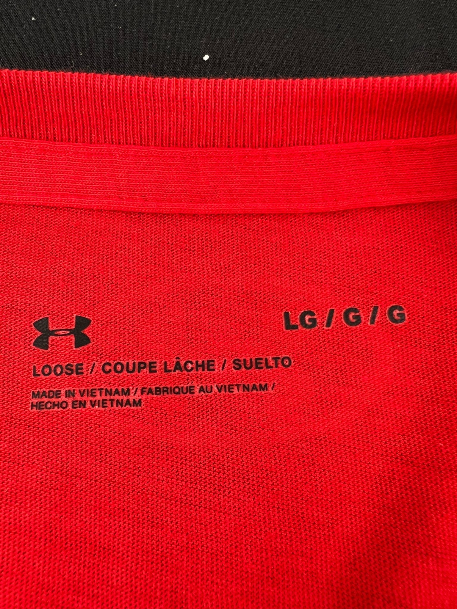 Close up of Under Armour sizing and material tag on red t-shirt