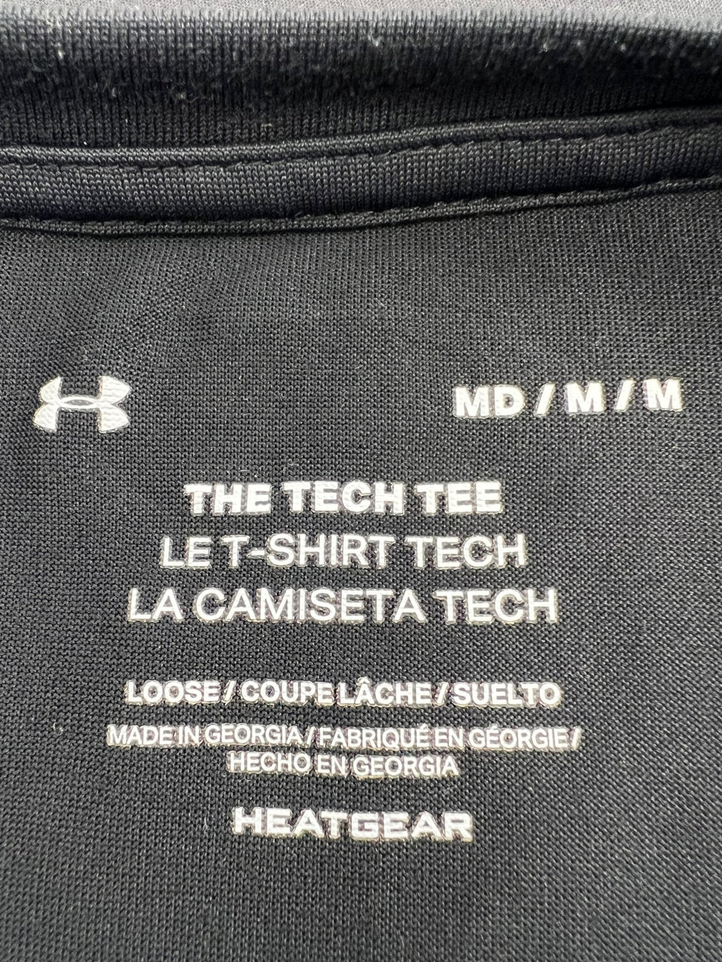 Closeup of inner neck label showing Under Armour Tech Tee details, size medium, and HeatGear fabric
