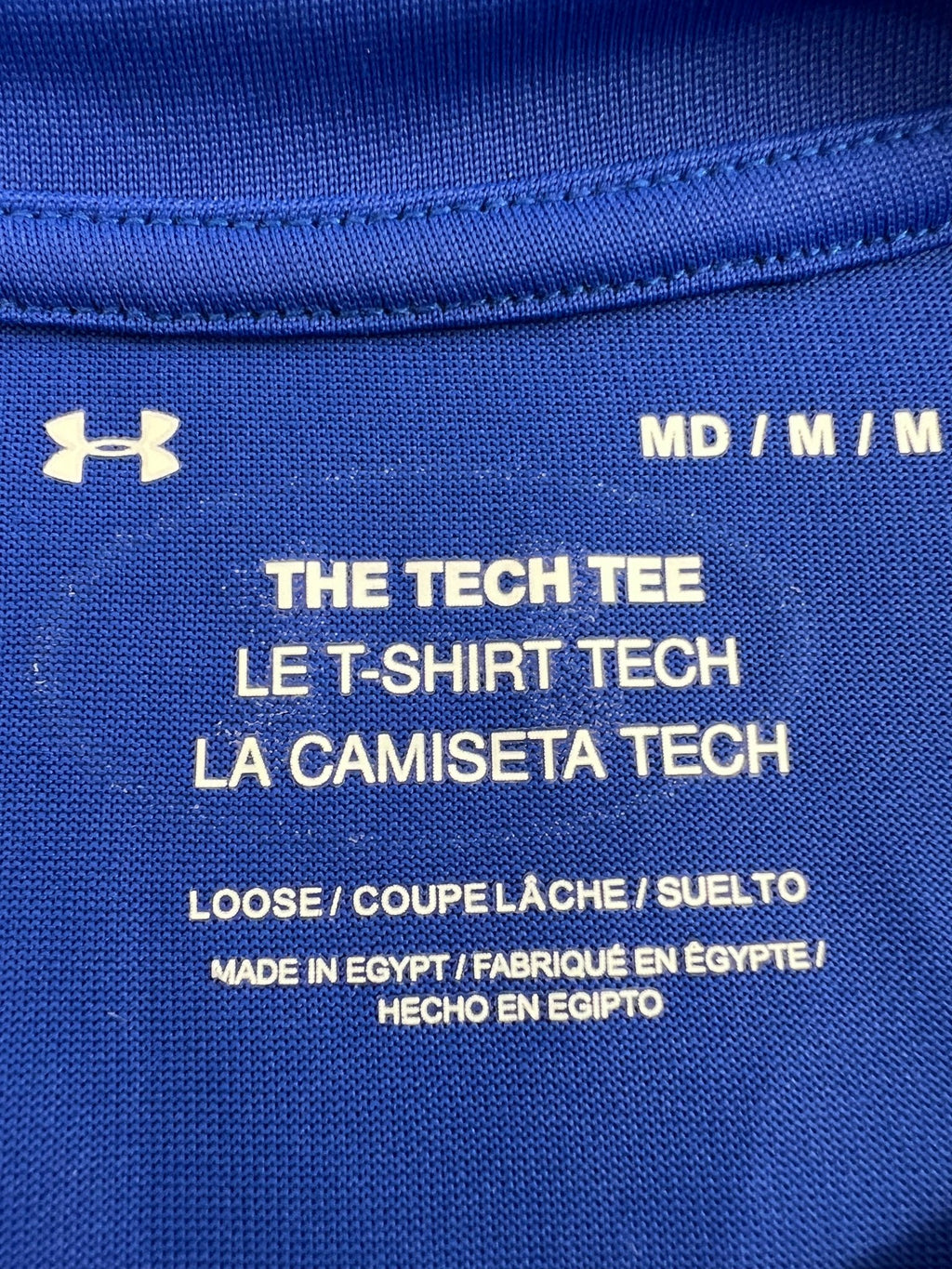 Closeup of Under Armour Tech Tee shirt tag showing size medium and care information