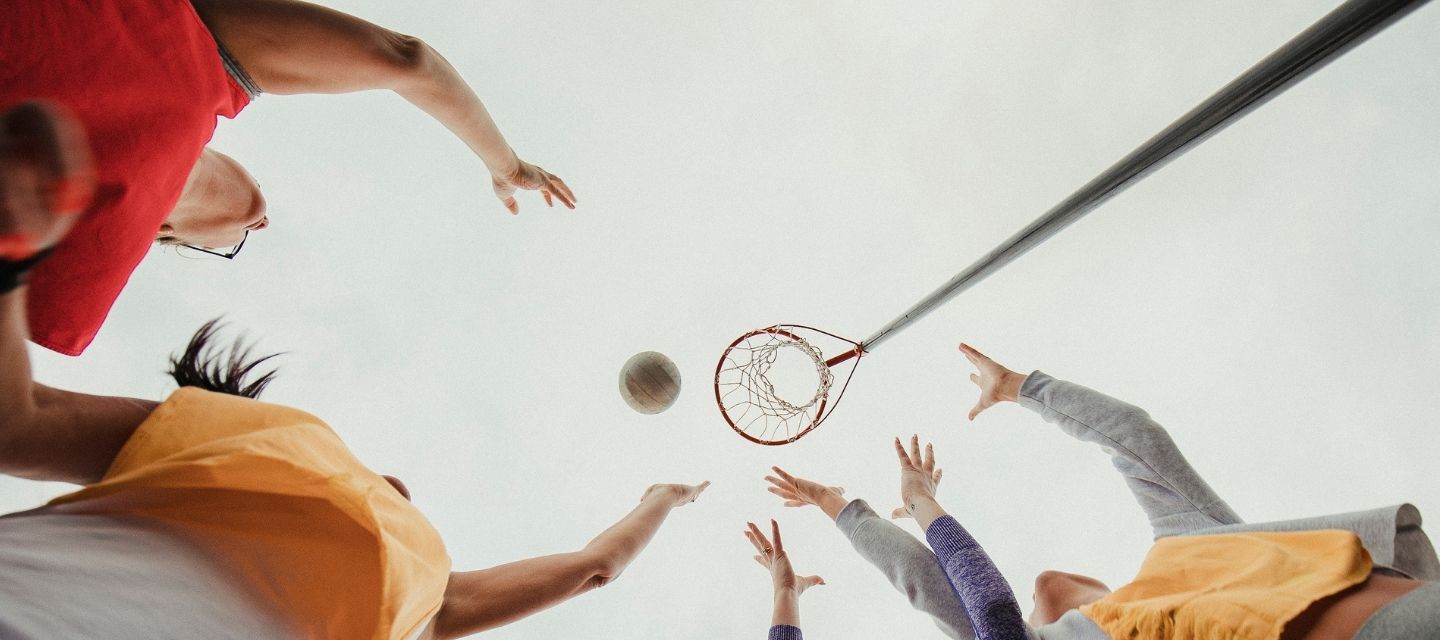 People playing volleyball from a low angle with a clear sky background