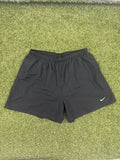 Front view of Nike Dri-FIT black running shorts on grass