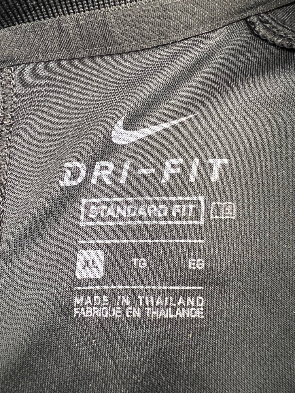 Close-up of Nike Dri-FIT label and size details inside polo top