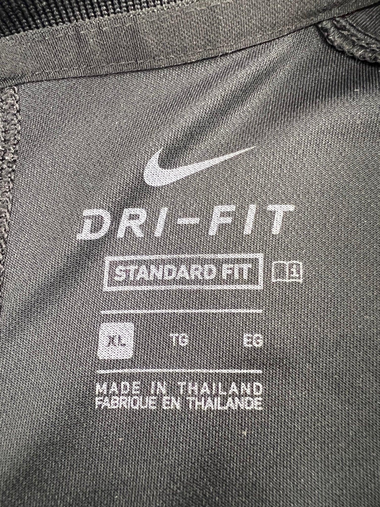 Close-up of Nike Dri-FIT label and size details inside polo top
