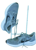 Pair of used grey Nike Downshifter running trainers size 11 displayed on artificial grass with green backdrop
